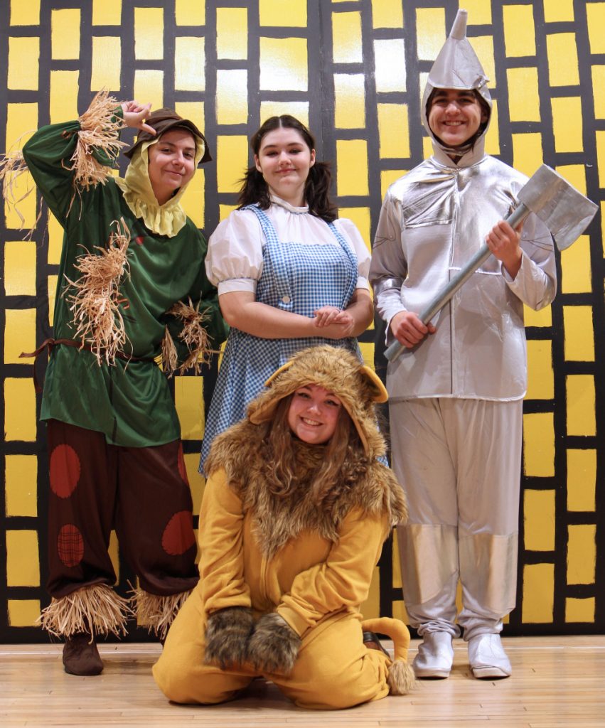 In front of the yellow brick road: Front row: Khloe Trussell as the Cowardly Lion. Back row from left: Jacob Boyette as the Scarecrow, Rozzalin Wallace as Dorothy, Issac Perry as the Tin Man.