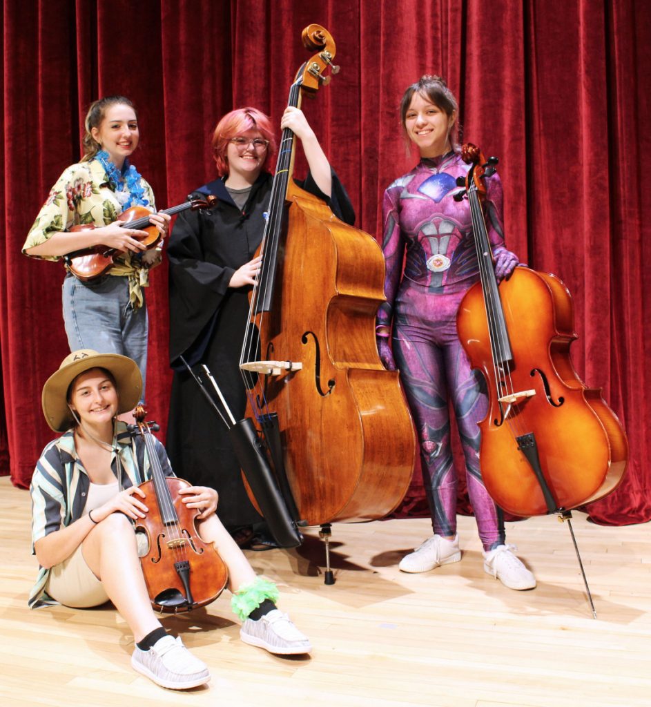 Pictured are students, in costume, from the John Marshall High School Strings program who will perform with their classmates and middle school students. Seated: A.C. Cumberledge. Standing from left: Cora Spielvogel, Grey Woods and Annadra Dudley. 